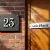 Huisnummer 23 op bakstenen muur naast Familie Johnson naamplaat op houten deur, hoogwaardige custom signage