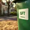 Is een gft-container sticker verplicht? 1 Groene GFT-container met officiële gemeentelijke sticker op Nederlandse straat met bakstenen bestrating