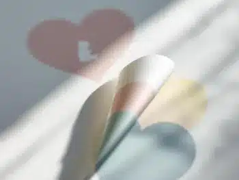 Pastelkleurige geboorteaankondiging stickers die van witte ondergrond loslaten, met baby silhouetten in roze, blauw en geel