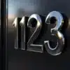 Chrome huisnummer stickers "123" op zwarte metalen deur met perfecte hechting en glanzende afwerking