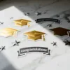 Elegante feestelijke stickers met gouden afstudeerpetjes, zwart-witte felicitatiebanner en zilveren sterren op wit marmer