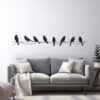 Muursticker Vogels op een draad op de muur boven een bank